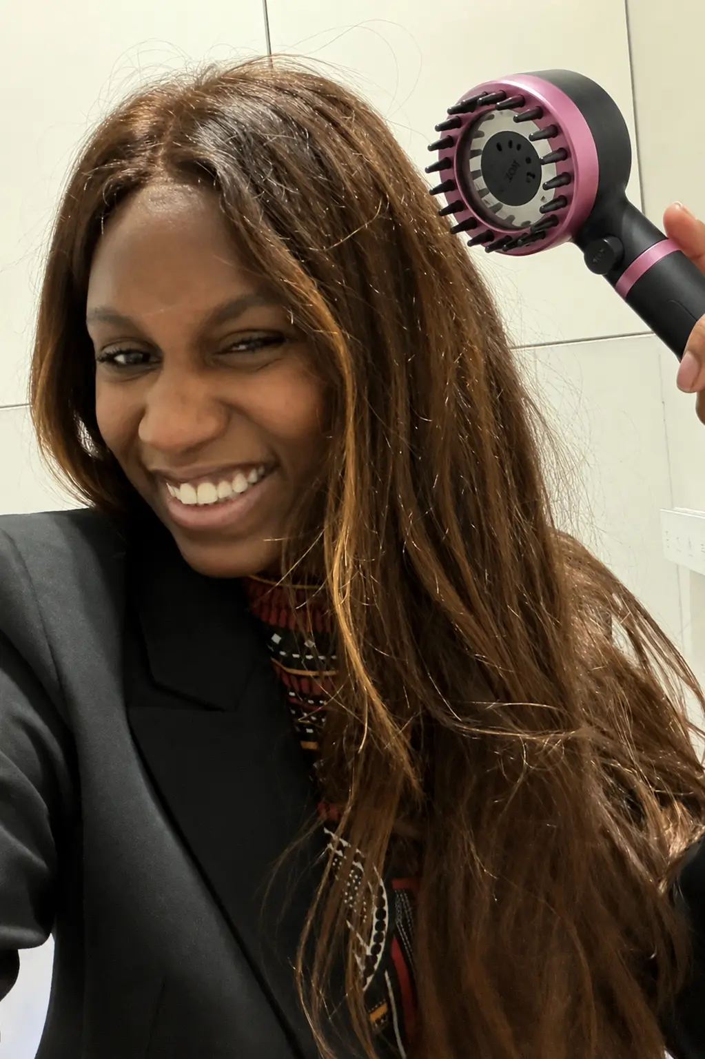 Customer holding a black and pink RAINLY shower head while styling her hair